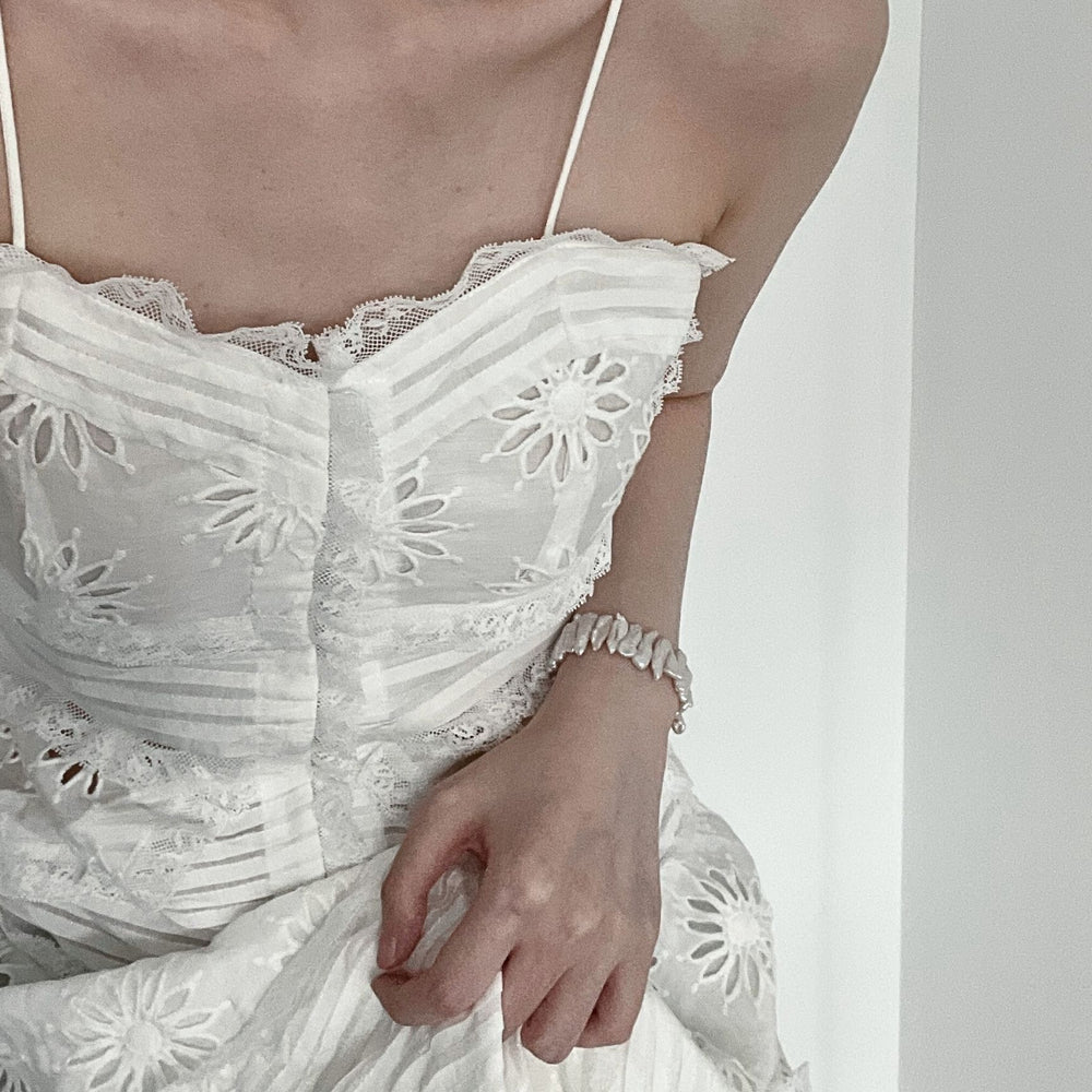 
                      
                        Stylish woman wearing a baroque pearl bracelet paired with a matching necklace in a floral dress
                      
                    