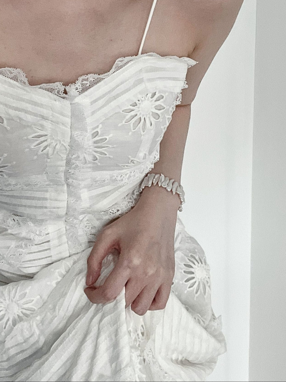 Elegantly styled baroque pearl bracelet worn on a hand, complementing a floral dress