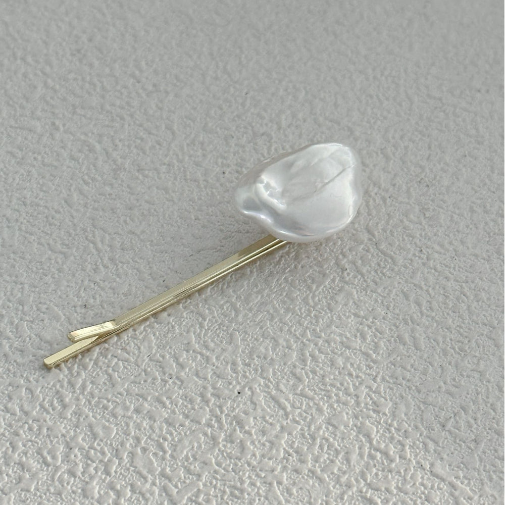 
                      
                        Elegant Baroque pearl hair clip on a textured surface, perfect for adding style to any hairstyle
                      
                    