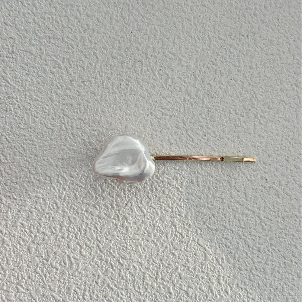 
                      
                        Elegant Baroque pearl hair clip on a textured surface for stylish hair accessories
                      
                    