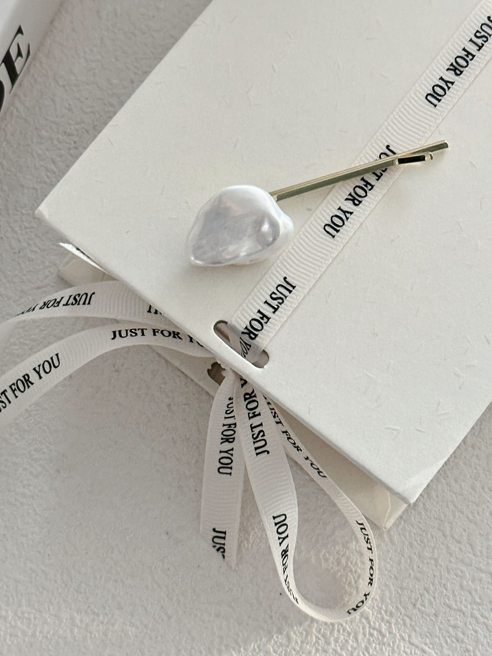Elegant Baroque pearl hair clip on a notebook with decorative ribbon for stylish hair accessories