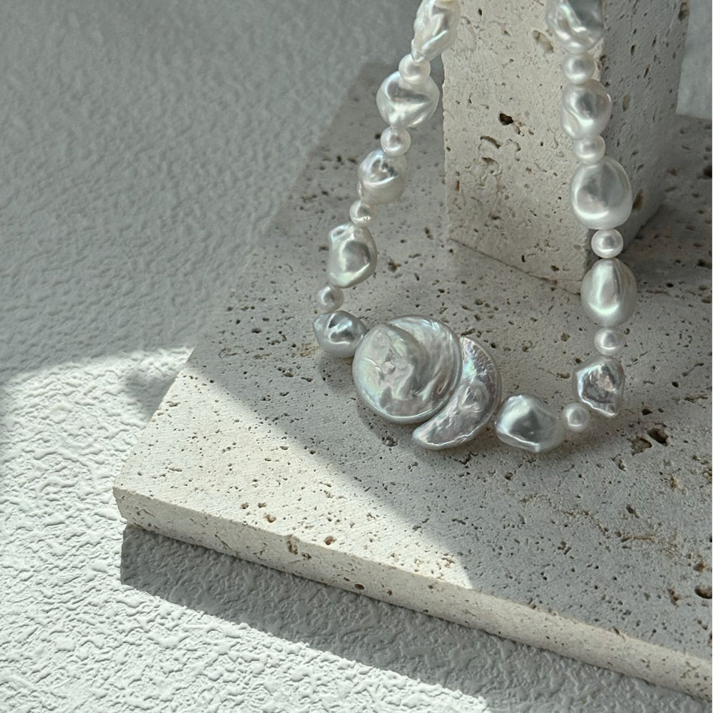 
                      
                        Elegant baroque pearl necklace showcasing unique shapes and lustrous shine on a textured surface
                      
                    