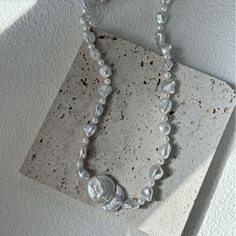 
                      
                        Baroque pearl necklace featuring unique shapes and a beautiful luster, displayed on a textured background
                      
                    