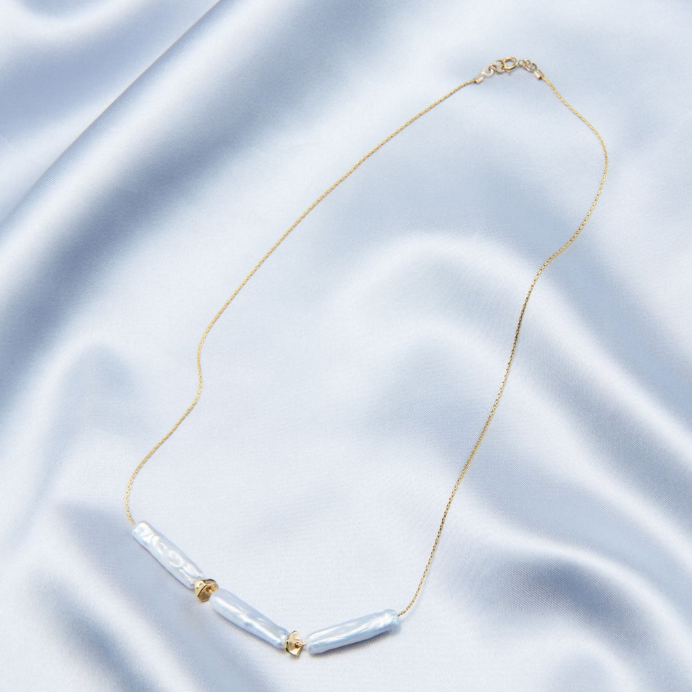 
                      
                        Elegant baroque necklace featuring blue pearls and gold accents on a delicate chain
                      
                    