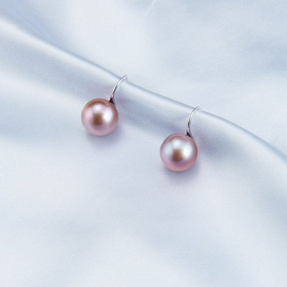 
                      
                        Elegant pearl earrings featuring beautiful pink pearls on a soft fabric background
                      
                    