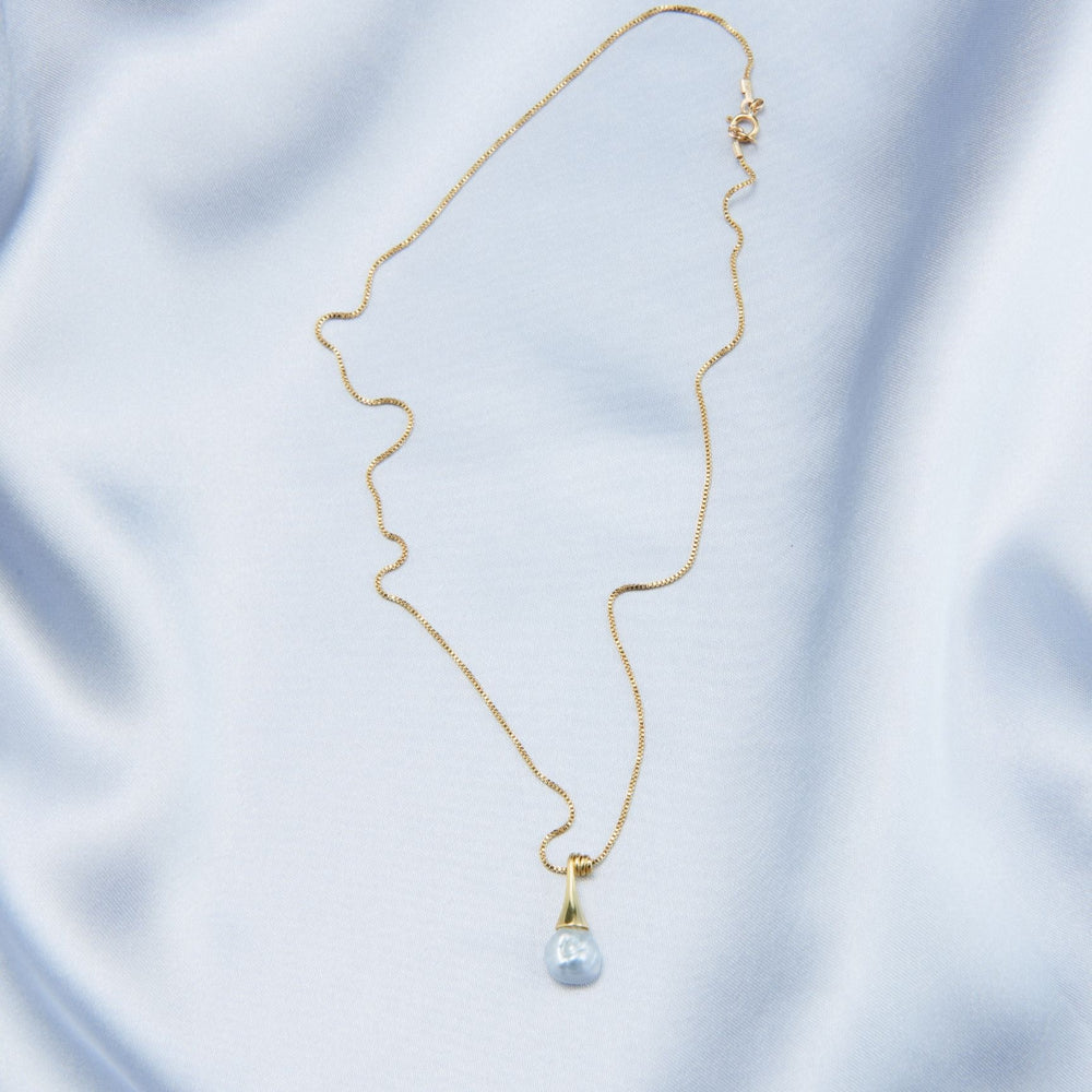
                      
                        Elegant pearl pendant necklace with a delicate gold chain and teardrop design on a soft silk background
                      
                    
