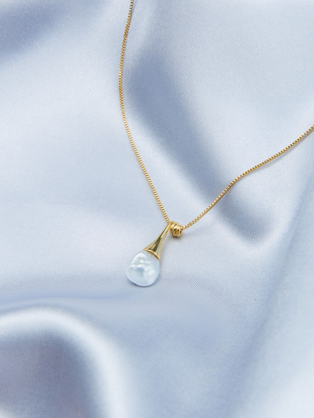 Elegant pearl pendant necklace in gold on a soft satin background for a chic look
