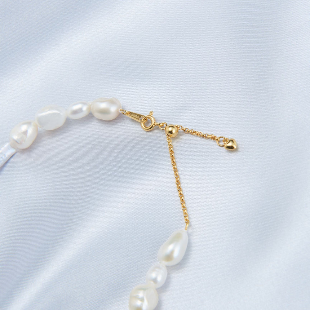 
                      
                        Close-up of a French baroque pearl necklace featuring elegant white pearls and a gold clasp
                      
                    