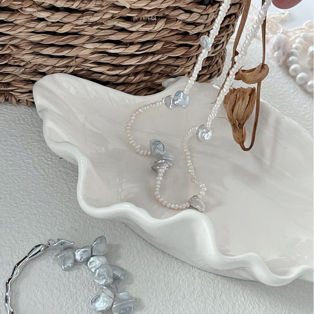 
                      
                        Handcrafted baroque necklace paired with a modern bracelet elegantly displayed on a decorative dish
                      
                    