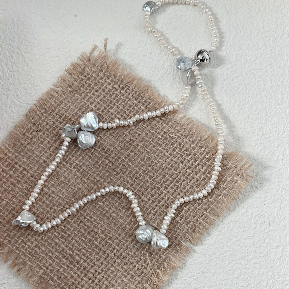 
                      
                        Handcrafted baroque necklace featuring unique pearls on a textured fabric background
                      
                    