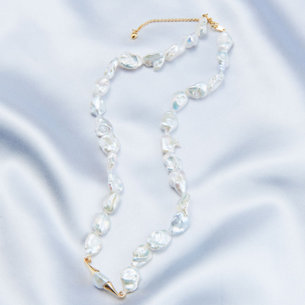 
                      
                        Elegant necklace featuring handcrafted baroque pearls on a soft satin background
                      
                    