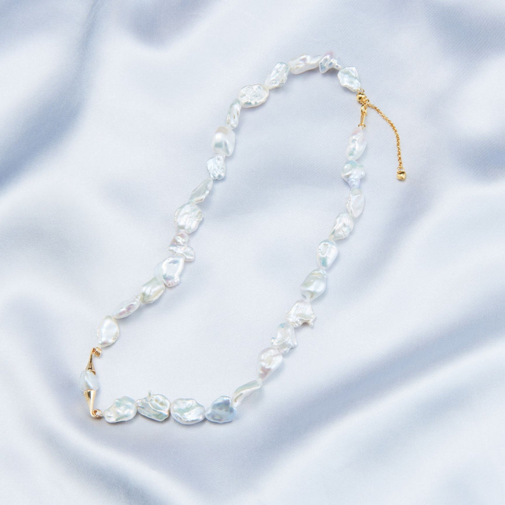 
                      
                        Elegant necklace featuring handcrafted baroque pearls on a soft silk background
                      
                    