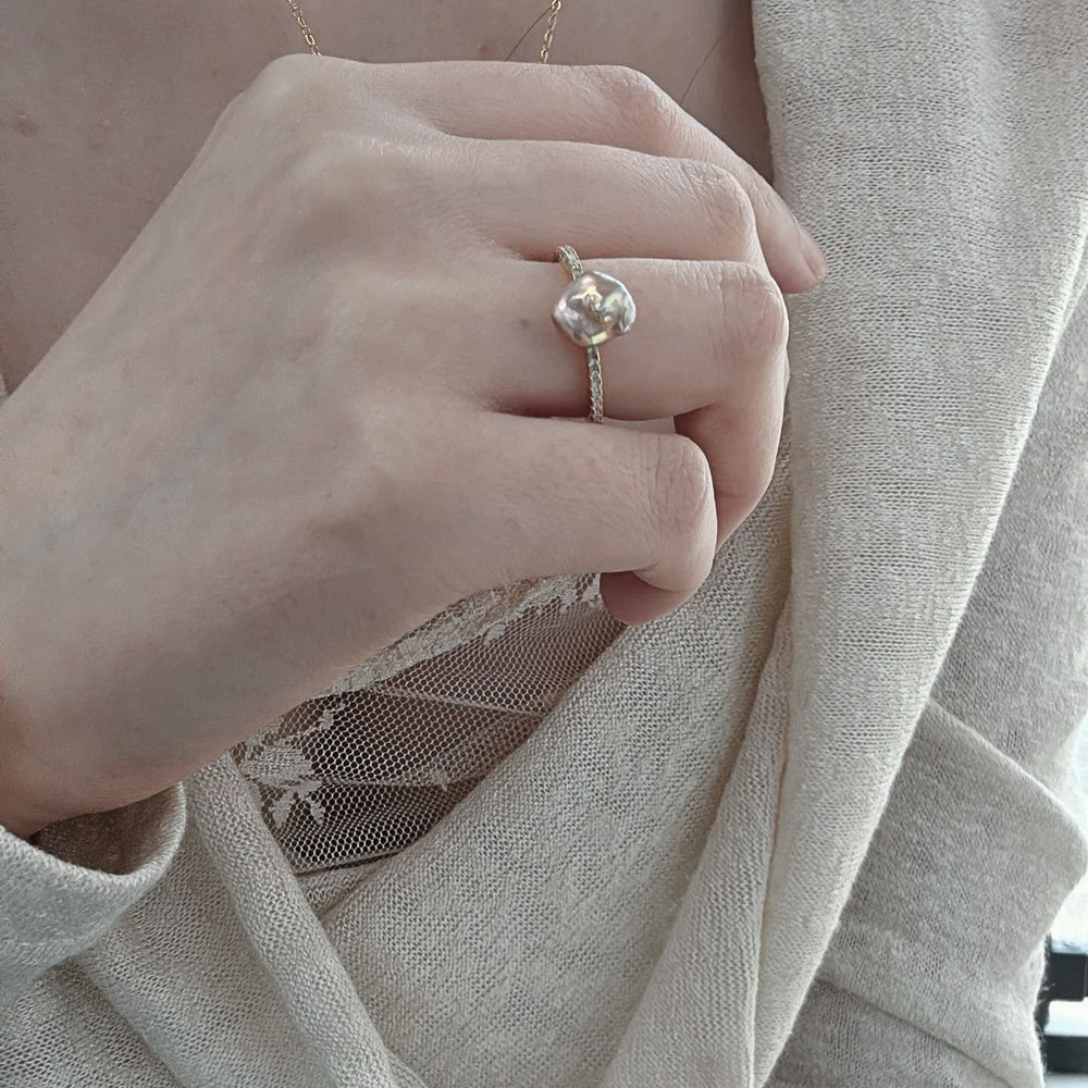 
                      
                        Handcrafted keshi pearl ring elegantly worn on a hand with a delicate gold chain necklace
                      
                    