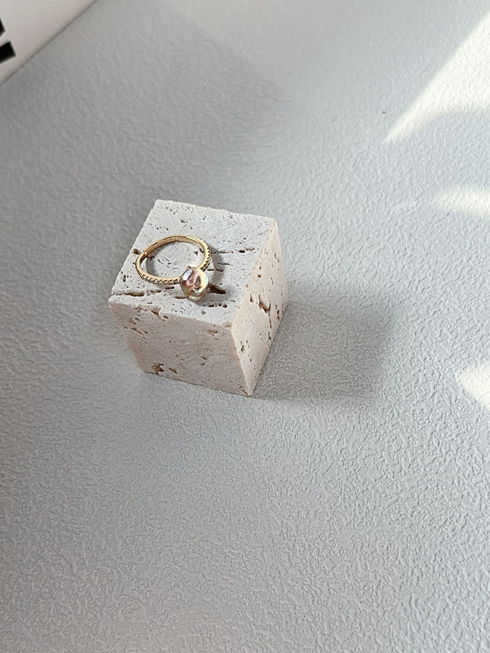 Handcrafted keshi pearl ring displayed on a textured stone block for elegant jewelry showcase