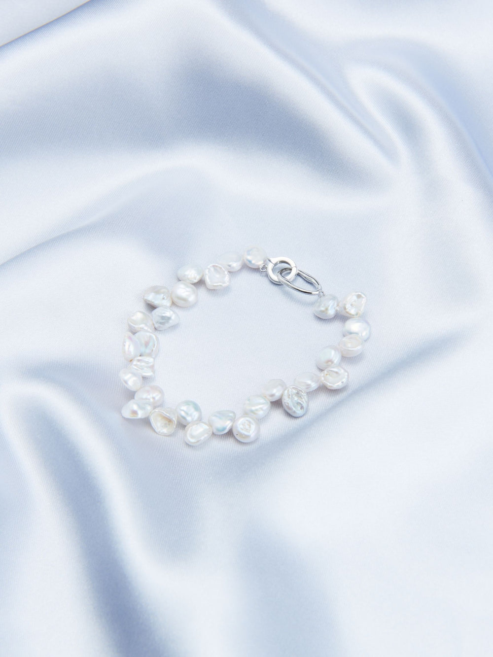 Stylish Keshi pearl bracelet featuring irregular shapes and a secure clasp on soft satin fabric