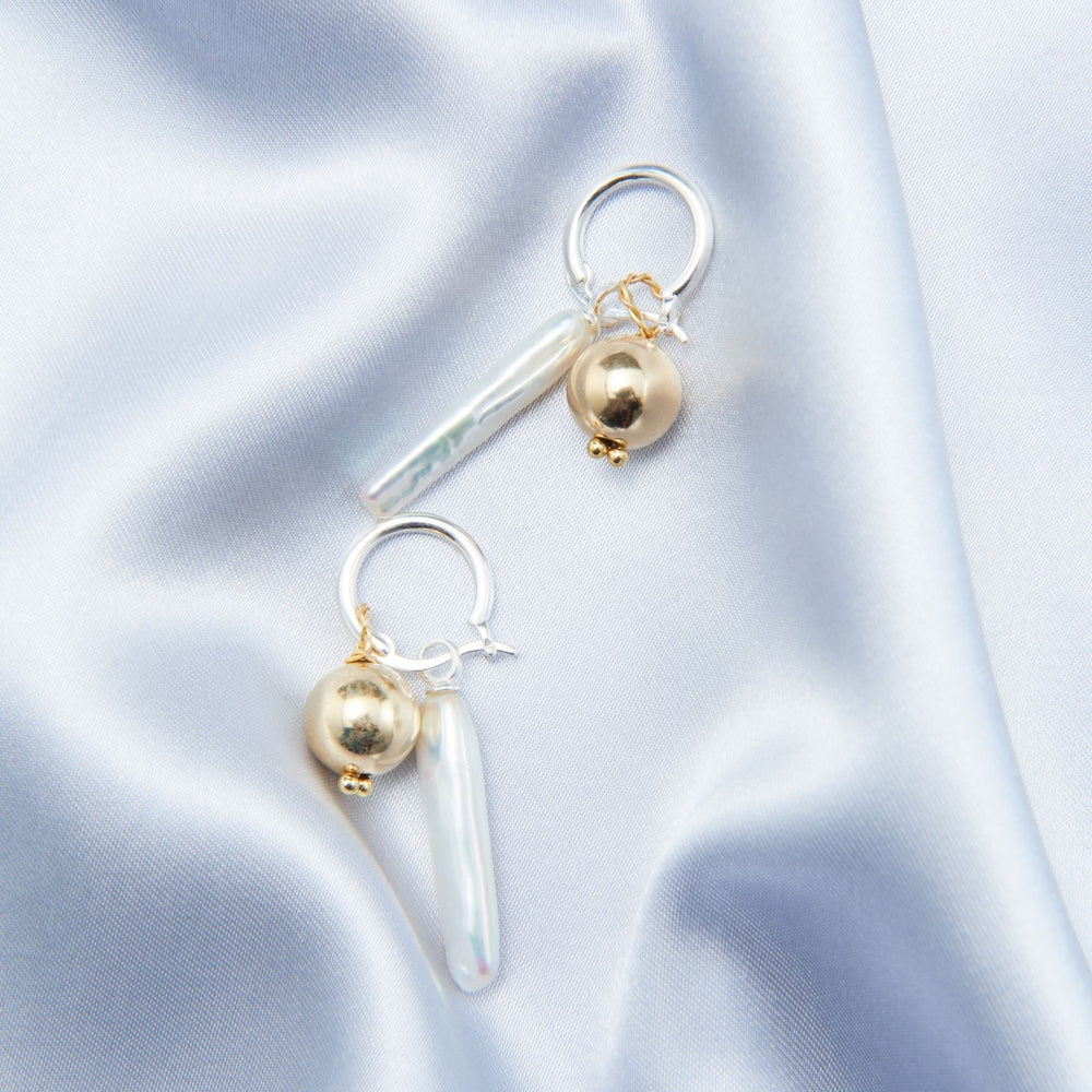 Luxury gold pearl earrings with a unique design featuring a pearl and sleek drop accent