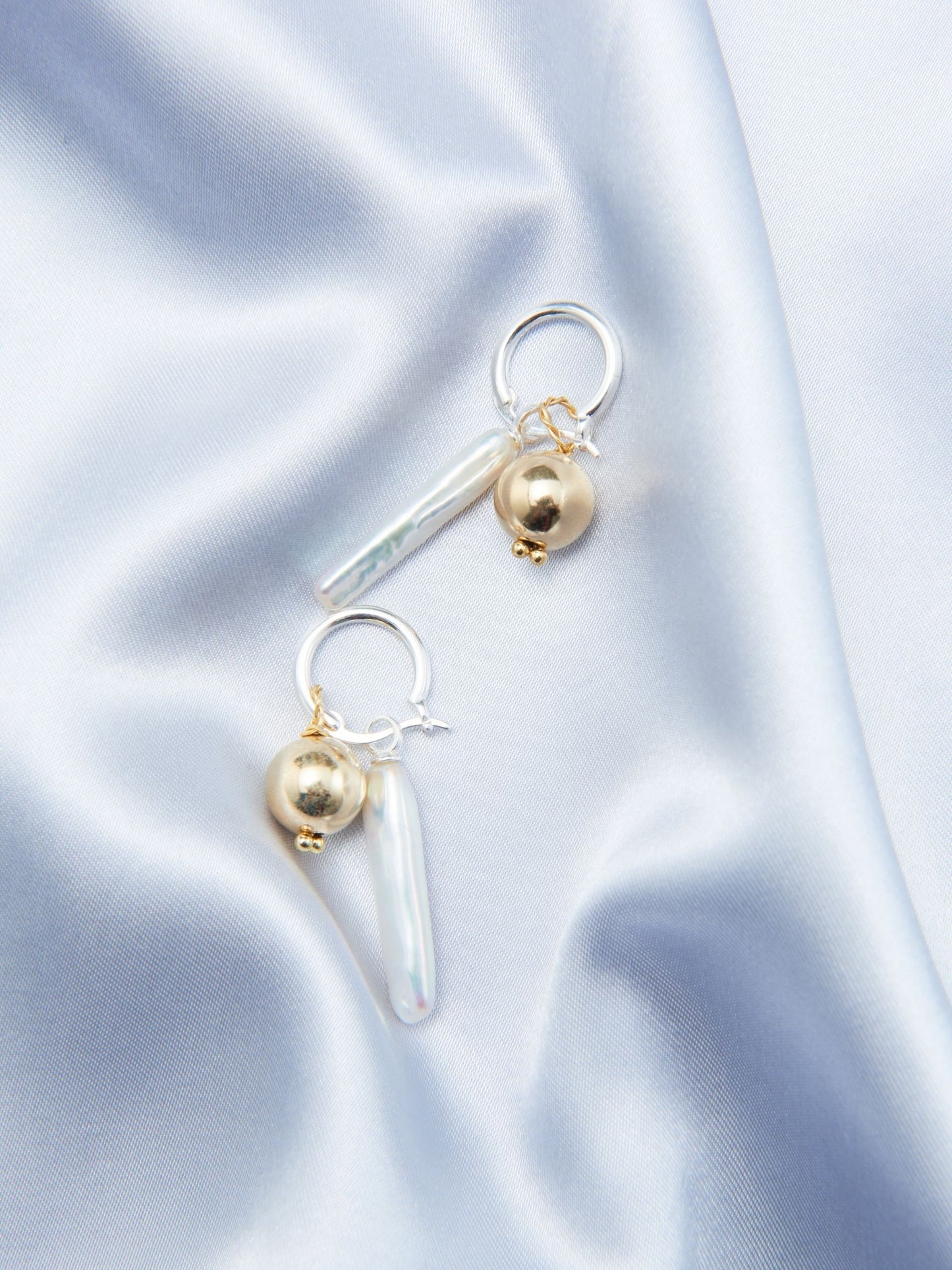 Luxury gold pearl earrings with a unique design featuring a pearl and sleek drop accent