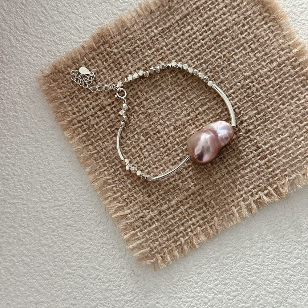 Elegant sterling silver pearl bracelet featuring a large pink pearl and delicate chain design