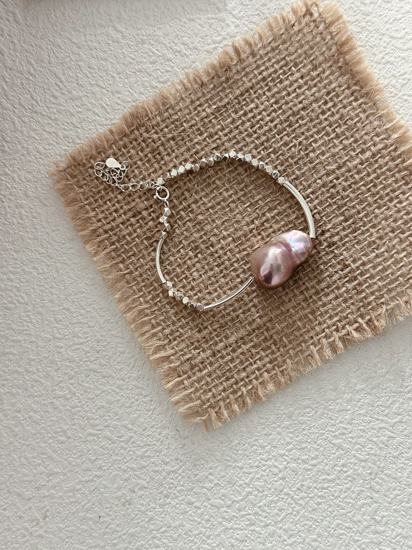 Elegant sterling silver pearl bracelet featuring a large pink pearl and delicate chain design
