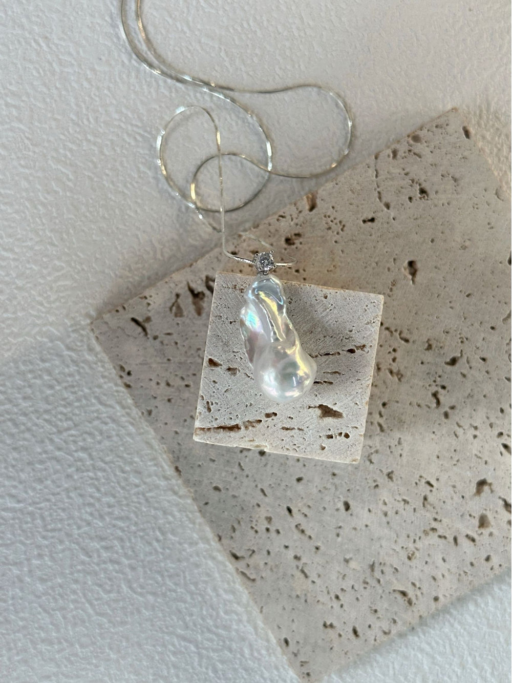 Unique baroque pearl necklace displayed on a textured stone background showcasing its natural shape