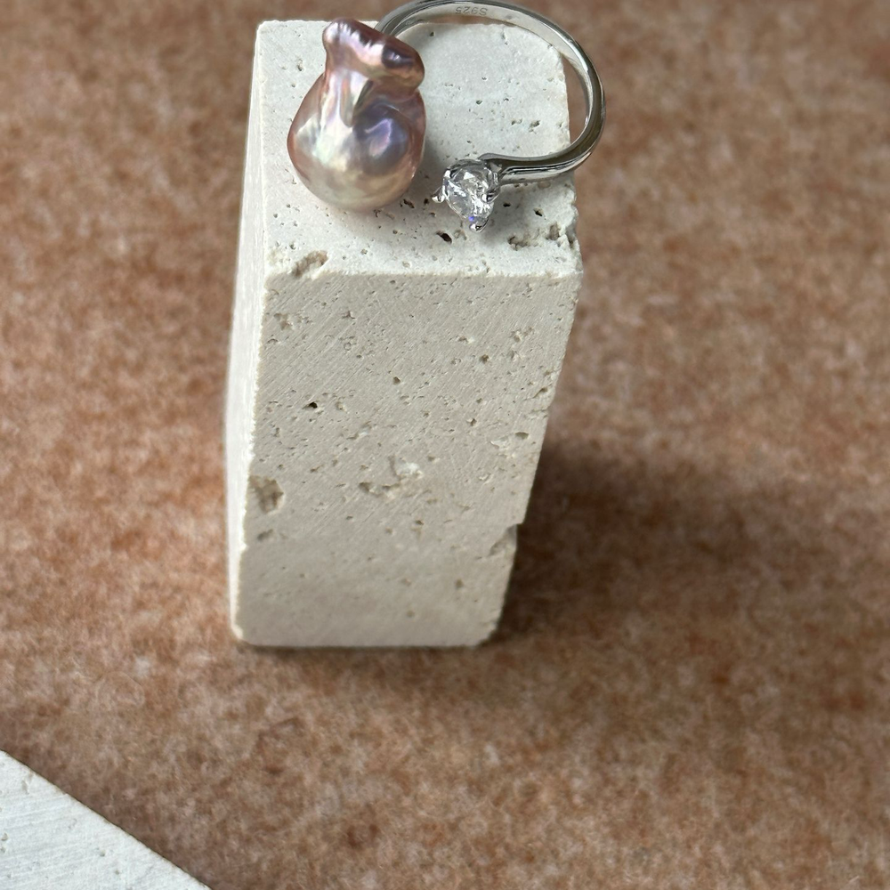 
                      
                        Unique baroque pearl ring set on a minimalist stone display with elegant detailing
                      
                    