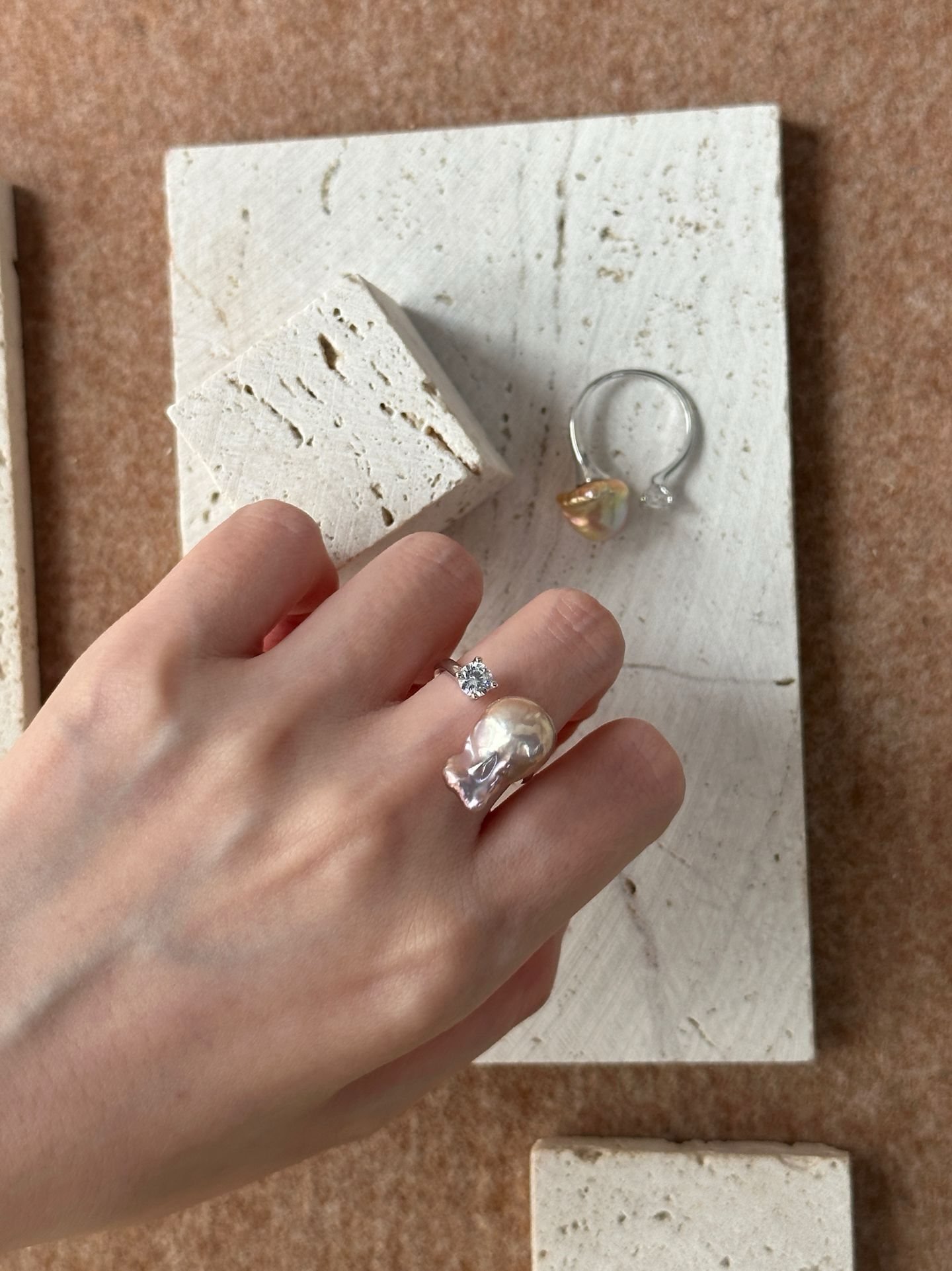 Elegant hand wearing a unique baroque pearl ring paired with minimalist silver accessories
