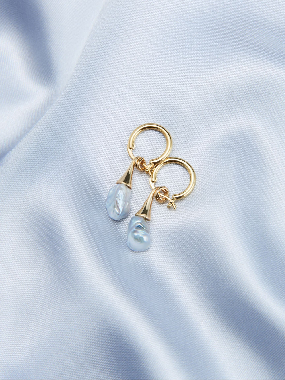 Elegant unique pearl drop earrings with gold accents on a soft satin background