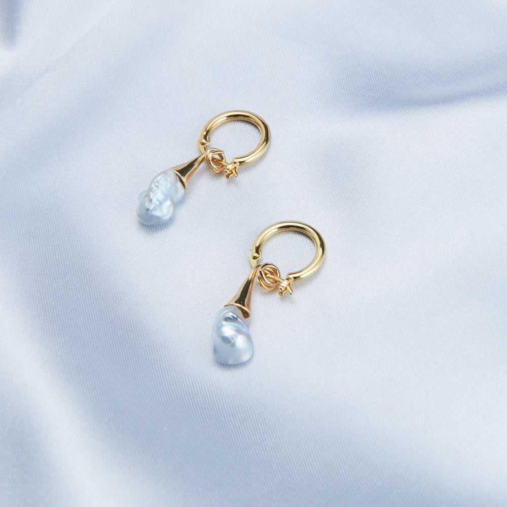 
                      
                        Unique pearl drop earrings by Pearlra featuring elegant gold hooks and delicate blue pearls
                      
                    
