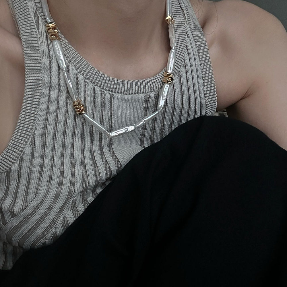 
                      
                        Unique pearl necklace design featuring silver and gold accents worn with a stylish outfit
                      
                    