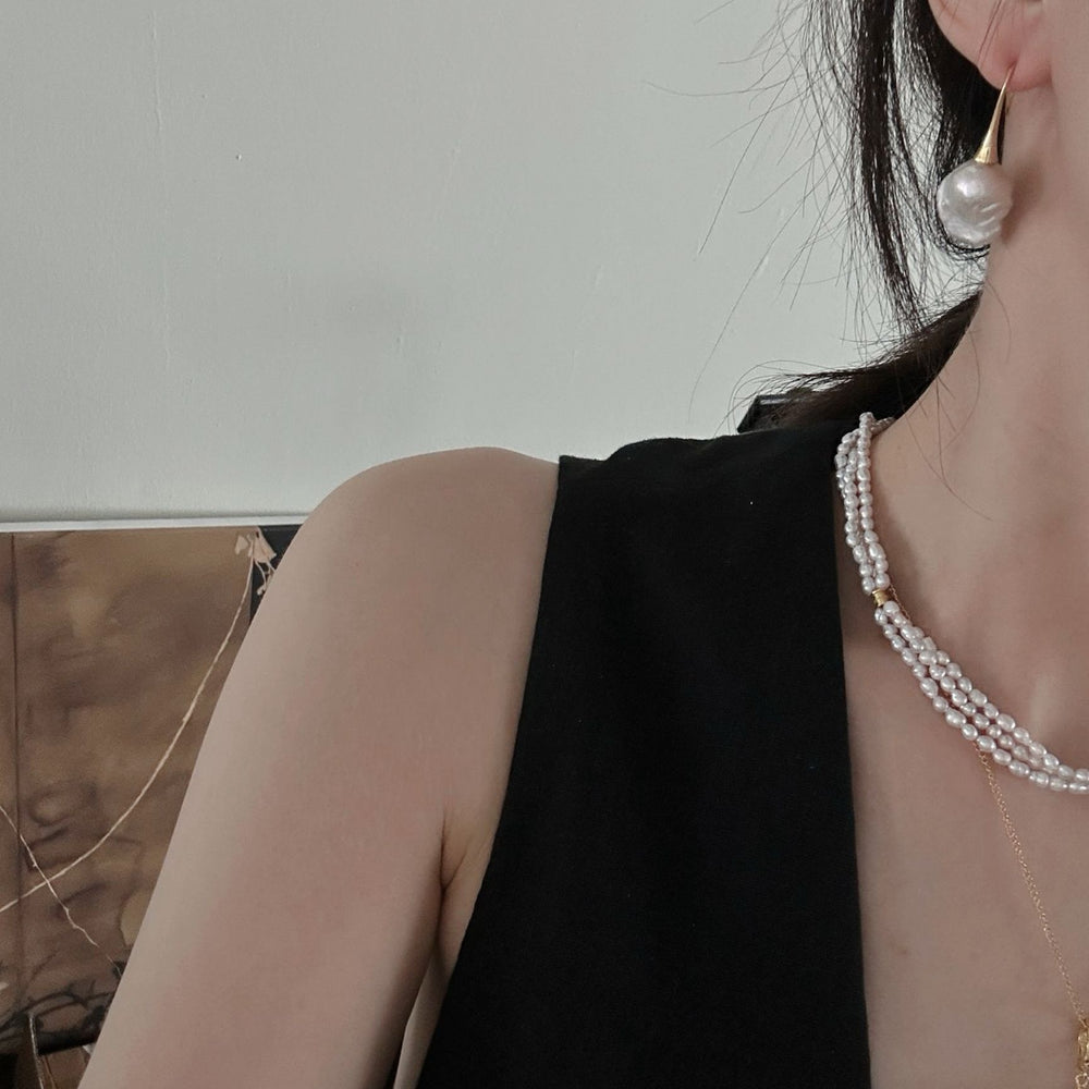 
                      
                        18K Gold Plated Baroque Pearl Stud Earrings worn with layered pearl necklaces on woman in black top
                      
                    